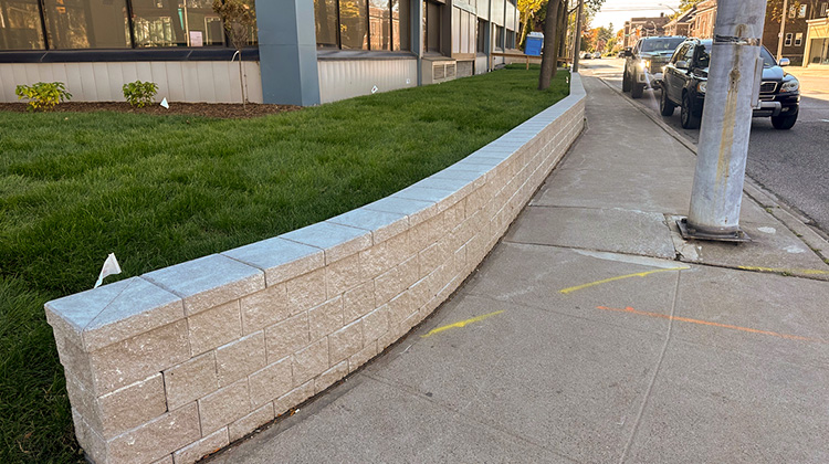 New retaining wall construction featuring fresh soil and sod installation at Windsor Health Unit (Ouellette Ave).